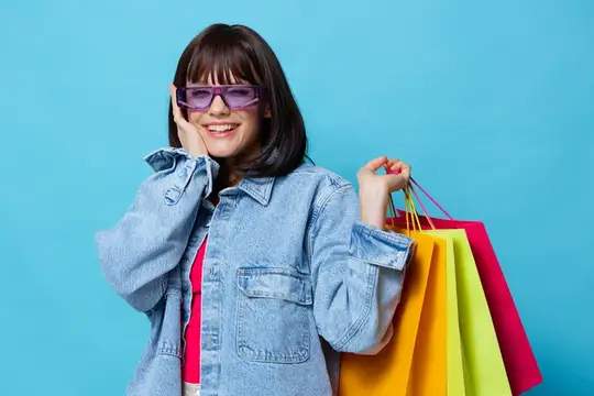 Улыбающаяся девушка в фиолетовых очках с разноцветными пакетами после шопинга
