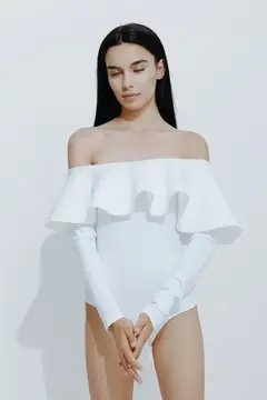 Брюнетка в белом купальнике с воланами на белом фоне