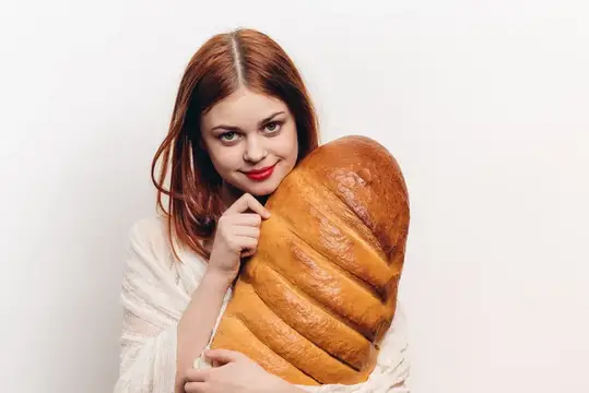 Эмоциональная женщина с батоном хлеба в руках, макияжем, рыжая модель