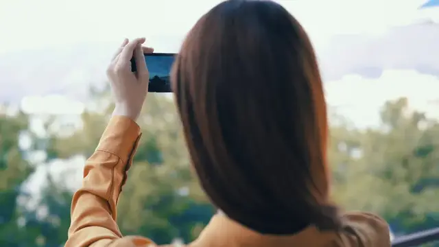 Высококачественная фотография: женщина с телефоном в руках фотографирует природу на открытом воздухе, панорама