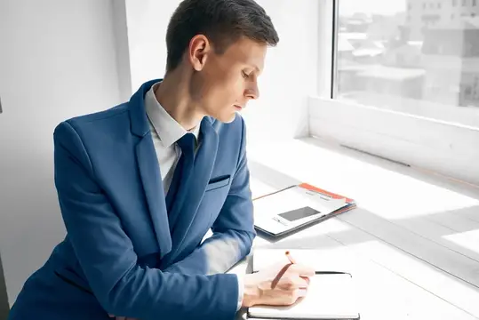 Деловой мужчина в костюме рядом с документами у окна