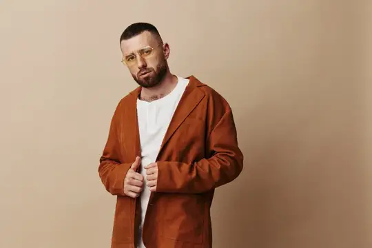 Молодой мужчина, изолированный на фоне, красивый, с бородой, стоит с выражением недовольства и серьёзности