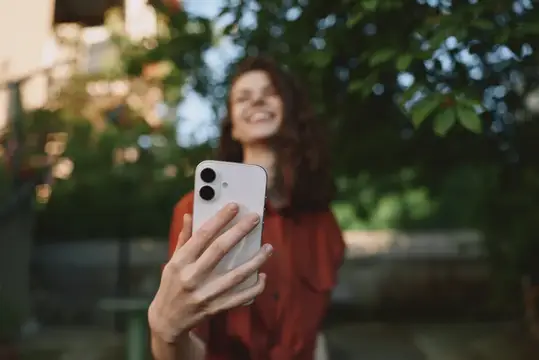 Улыбающаяся девушка делает селфи на смартфон в саду