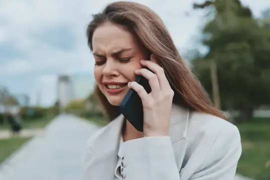 Молодая женщина хмурится во время неприятного телефонного разговора на улице