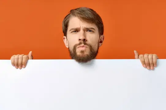 Бородатый мужчина выглядывает из-за белого листа на оранжевом фоне