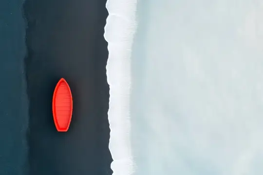 Красная лодка плывёт по тёмной воде у белого берега