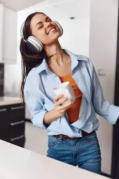 Молодая женщина наслаждается музыкой и кофе на кухне