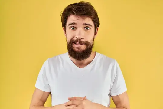 Удивлённый бородатый мужчина в белой футболке на жёлтом фоне