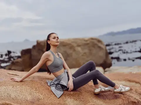 Спортивная девушка отдыхает на камне у моря