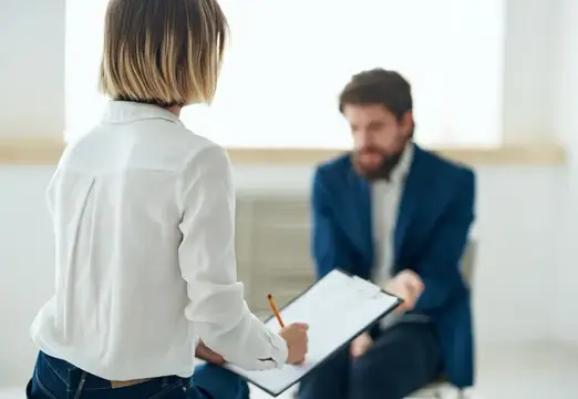 Женщина с планшетом беседует с бородатым мужчиной в офисе