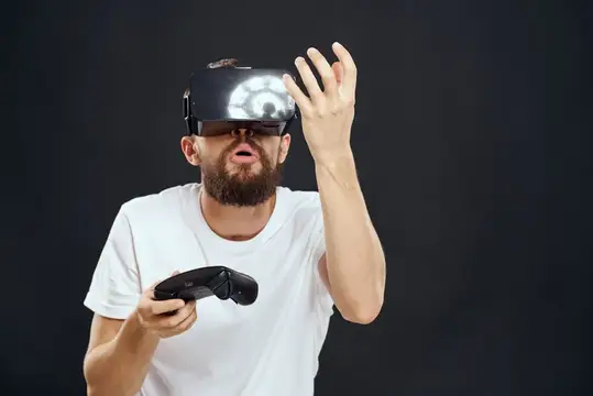 Бородатый мужчина в VR-очках тянет руку вперёд с контроллером