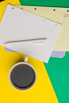 Чашка кофе и стопка бумаг на ярком жёлто-зелёном фоне