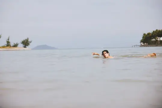 Улыбающийся азиатский мужчина наслаждается активными водными видами спорта во время отпуска на тропическом пляже