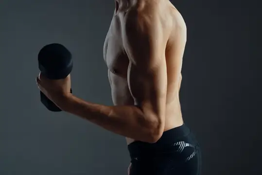 Спортивный мужчина с гантелями выполняет тренировочные упражнения для фитнеса