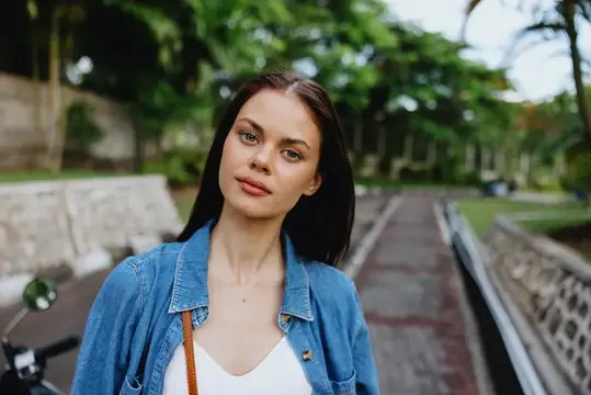 Портрет брюнетки, улыбающейся с зубами, идущей на улице на фоне пальм в тропиках