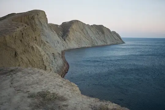 Обрывистые скалы над спокойным морем на рассвете