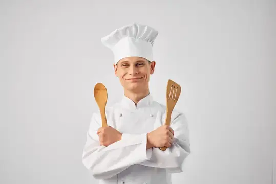 Весёлый шеф-повар-мужчина с кухонной утварью, работающий в ресторане, персонал