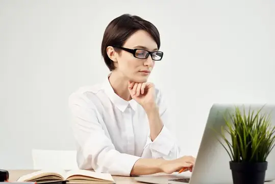 Задумчивая женщина в очках за работой с ноутбуком