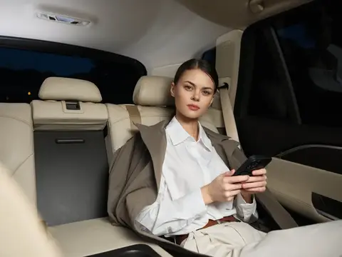 Молодая женщина со смартфоном на заднем сиденье автомобиля