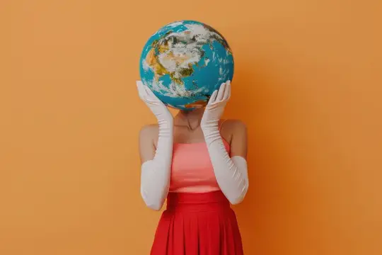 Женщина в белых перчатках закрывает лицо глобусом на оранжевом фоне