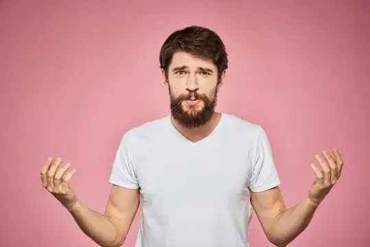 Весёлый бородатый мужчина в белой футболке, кадр обрезан, на розовом фоне
