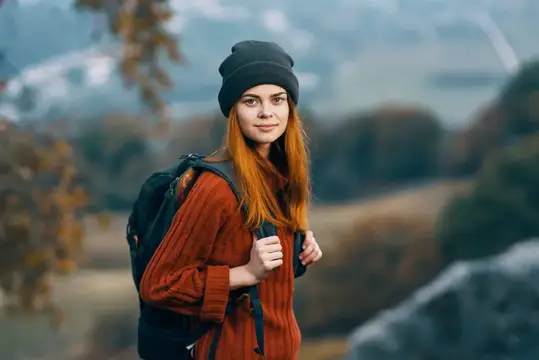Женщина с рюкзаком в горах среди осенней природы отправляется в приключение