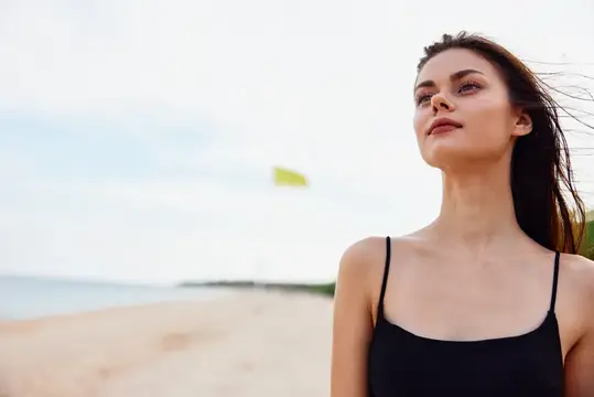 Молодая темноволосая женщина на песчаном пляже у моря