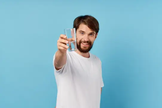 Улыбающийся бородатый мужчина протягивает стакан воды на голубом фоне