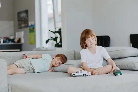 Рыжеволосые мальчики играют с машинками на диване