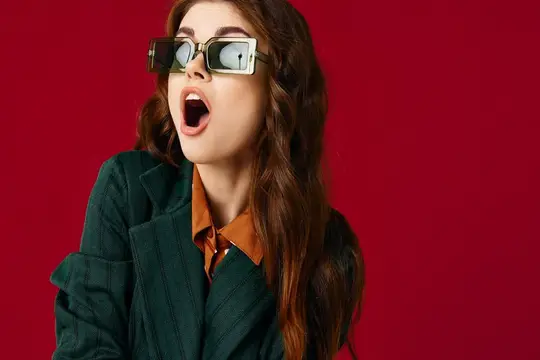 Удивлённая девушка в солнцезащитных очках с открытым ртом на красном фоне