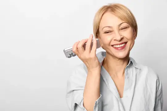 Пожилая женщина улыбается, общаясь по смартфону