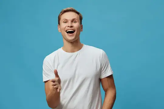 Улыбающийся парень в белой футболке указывает пальцем на синем фоне