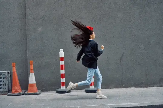 Стильная женщина бежит по улице на фоне города
