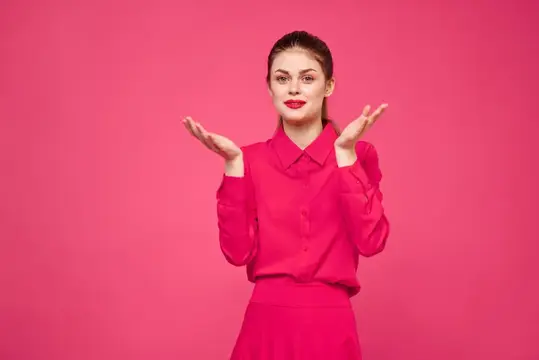 Женщина на розовом фоне в модной одежде, с ярким макияжем и причёской, модель