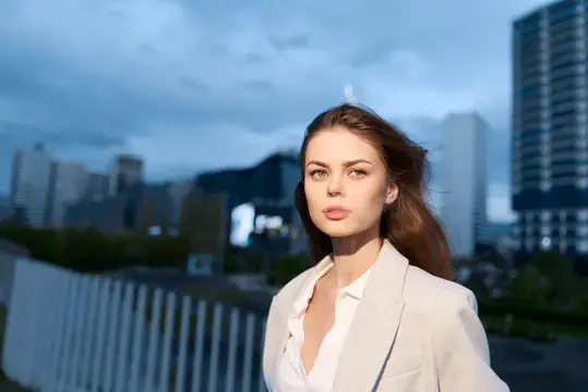 Молодая женщина в светлом пиджаке на фоне вечернего города