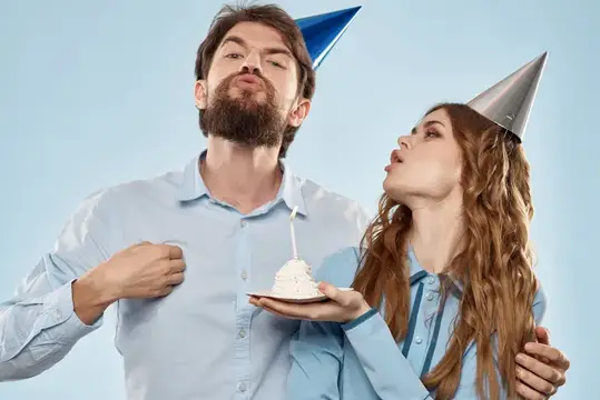 Молодые мужчина и женщина на корпоративе с тортом на изолированном фоне