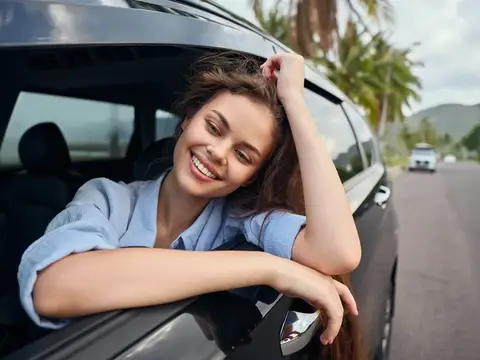 Улыбающаяся девушка высунулась из окна автомобиля в тропиках