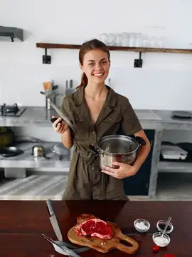 Улыбающаяся девушка с ножом и кастрюлей на кухне