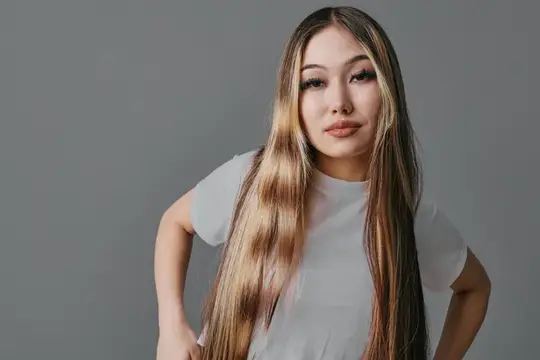 Азиатская девушка с длинными светлыми прядями в серой футболке