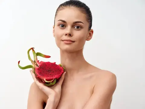 Молодая женщина с драконьим фруктом в руке на белом фоне