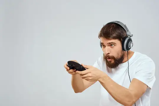 Бородатый мужчина в наушниках увлечённо играет в видеоигру