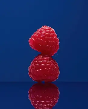 Две спелые малины на синем фоне с отражением