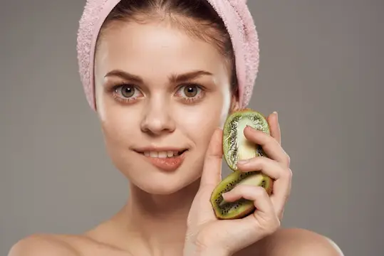 Женщина с обнаженными плечами держит в руках киви