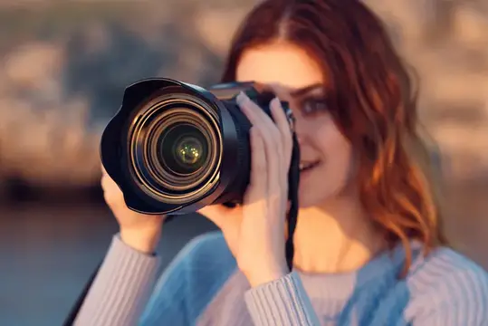 Рыжеволосая девушка смотрит в объектив фотокамеры на закате