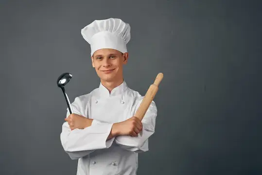Мужчина в форме шеф-повара работает на кухне ресторана, занимаясь приготовлением блюд