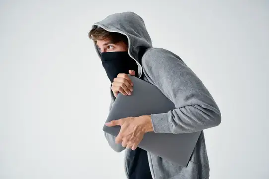 Мужчина в капюшоне и маске крадёт ноутбук