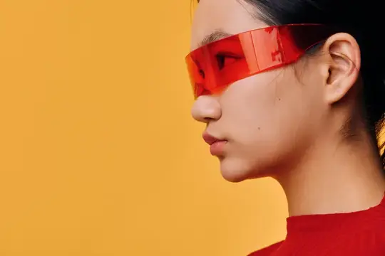 Азиатская девушка в красных футуристичных очках на жёлтом фоне