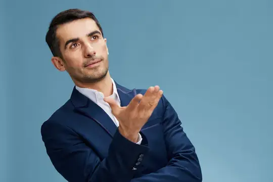 Задумчивый мужчина в синем костюме жестикулирует на голубом фоне