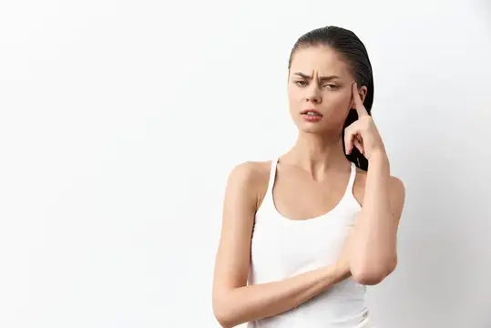 Задумчивая молодая женщина с пальцем у виска на белом фоне