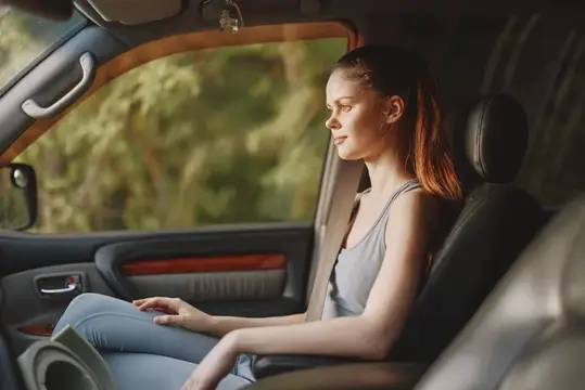 Рыжеволосая девушка спокойно сидит в салоне автомобиля